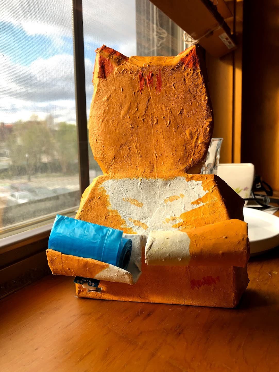 Paper mâché cat holding a litter bag, powered by an Arduino